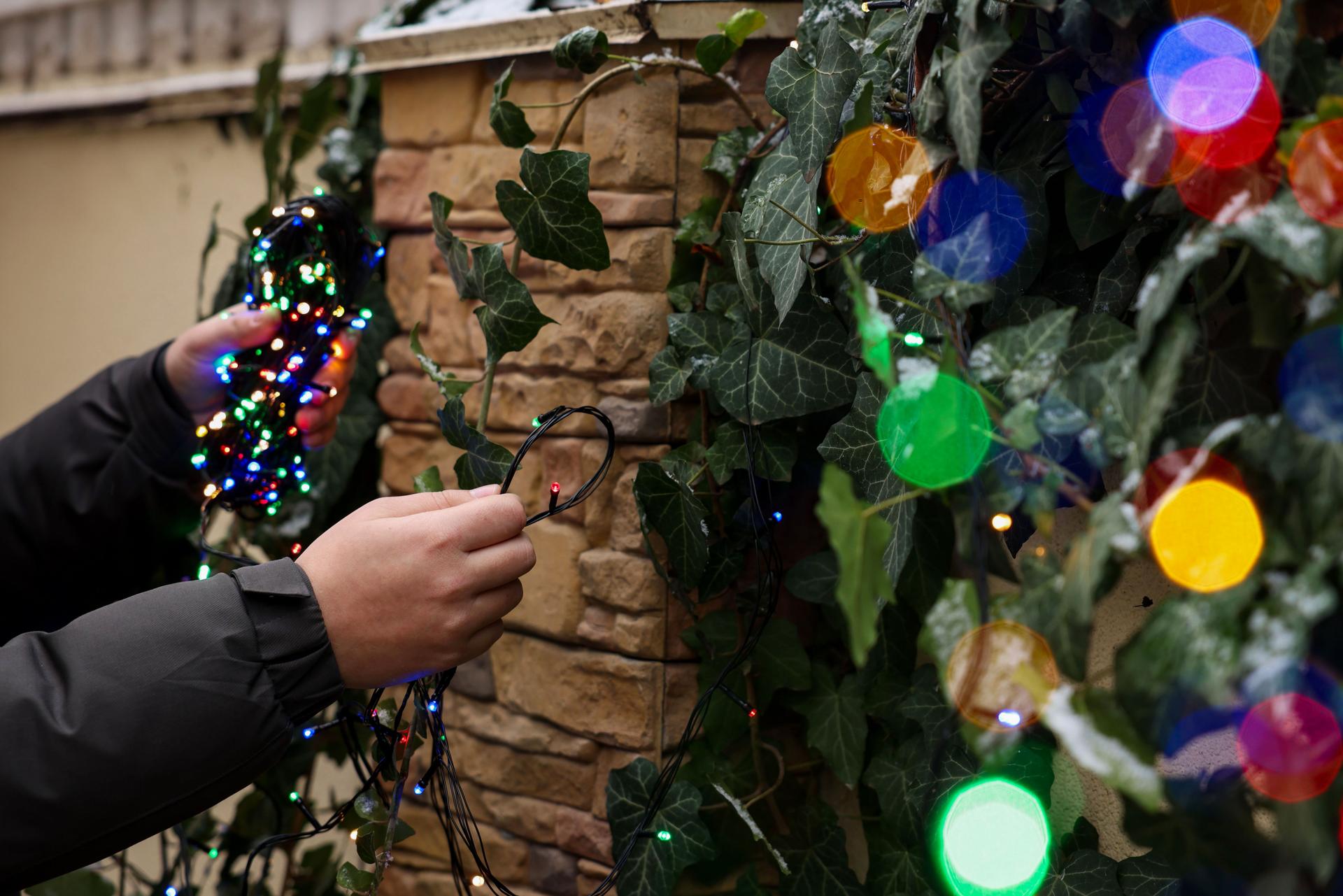 Man decorating house with Christmas lights outdoors, closeup